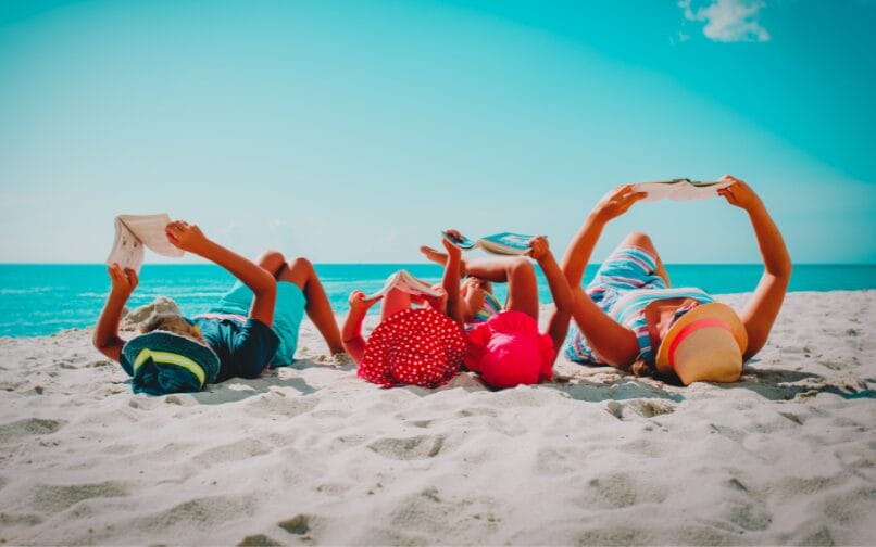 Familia leyendo en una playa.