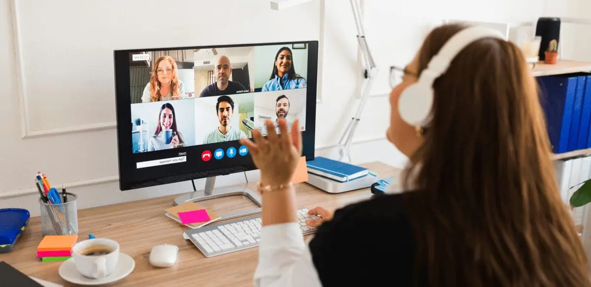 Una mujer participa en un videochat en su ordenador, conectándose con otras personas a través de una reunión virtual.