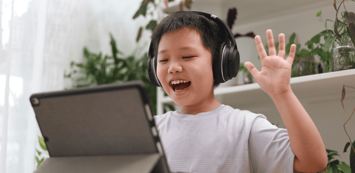 Un joven con auriculares sonríe mientras se entretiene con su ordenador portátil, mostrando alegría en su experiencia digital.