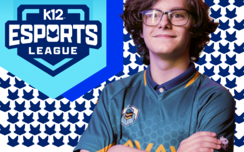 Una persona con una camiseta verde azulado de deportes electrónicos posa con los brazos cruzados delante de un fondo estampado con iconos repetidos en forma de zorro azul. A la izquierda, un gran logotipo azul en forma de escudo reza «K12 Esports League» con un emblema de zorro estilizado sobre el texto.